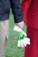 uma homem e mulher segurando mãos com flores foto