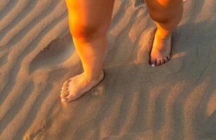 pés do uma mulher caminhando em suave de praia areia e Sol raios, com espaço para texto foto