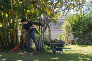 homem varrendo jardim gramado dentro elegante casa foto