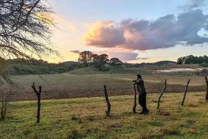 jovem homem pensativo e refletindo, olhando às a pôr do sol com lindo nuvens e espaço para texto foto