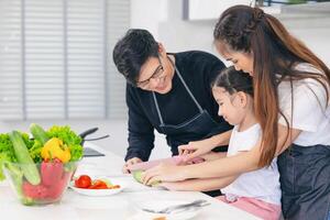 criança jogando cozinhar Comida com pai e mãe às casa cozinha. ásia família felicidade momento junto. foto