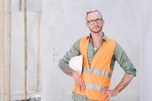 retrato construtor profissional engenheiro arquiteto capataz hipster trabalhador trabalhos dentro construção site, olhando Câmera confiante foto