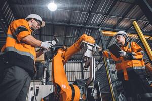 engenheiro equipe serviço robô Soldagem trabalhando dentro automação fábrica. pessoas trabalhador dentro segurança terno trabalhos robótico braço Programas programação ou substituindo parte dentro automatizado fabricação indústria tecnologia. foto