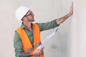 retrato construtor profissional engenheiro arquiteto capataz hipster trabalhador trabalhos dentro construção site, verificação drywall acabado trabalho foto