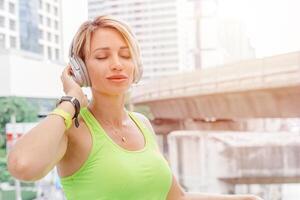 caucasiano mulher apreciar música com sem fio fone de ouvido tecnologia estilo de vida dentro cidade fundo foto