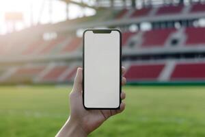 ai gerado mão segurando Smartphone com em branco tela de a futebol estádio em a fundo. generativo ai foto