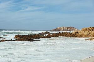 branco ondas batendo pedras em a oceano costa foto
