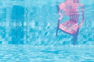 embaixo da agua Visão do Rosa plástico cadeira dentro natação piscina foto
