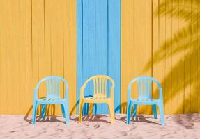 colorida plástico cadeiras contra amarelo e azul de madeira parede em areia foto