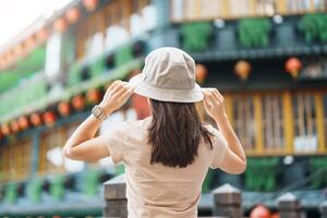 mulher viajante visitando dentro Taiwan, turista com chapéu passeios turísticos dentro Jiufen velho rua Vila com chá casa fundo. ponto de referência e popular atrações perto Taipei cidade . viagem e período de férias conceito foto