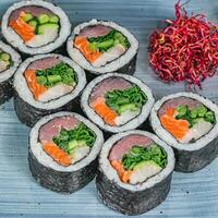 Sushi rolos com legumes e molho em uma azul prato foto