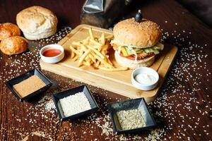 de madeira corte borda com hamburguer e francês fritas foto