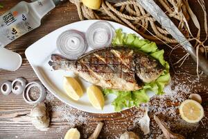 branco prato com peixe, limões, e alho foto