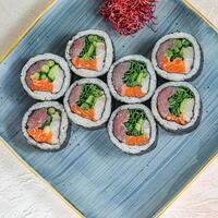 saboroso azul prato com uma variedade do Sushi e fresco legumes foto