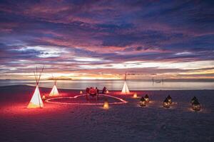 configuração de mesa para cerimônia de casamento na praia do pôr do sol. jantar de destino romântico, celebração de romance de aniversário de casal. jantar de união de arranjo de amor na costa da ilha. incrível vista para o mar do céu foto