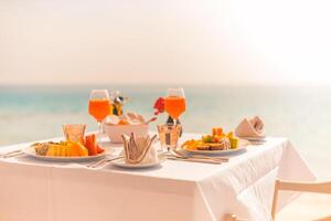 mesa de café da manhã de luxo lindo fundo do céu do mar tropical. manhã romântica idílica ama o tempo dos casais nas férias de verão. conceito de férias de romance de lua de mel. viagens e estilo de vida, destino gastronômico foto