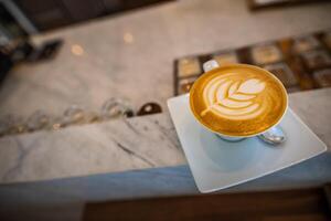 copo do café café com leite em madeira mesa e lindo café com leite arte. café com leite ou cappuccino com espumoso espuma, café copo topo Visão em mesa dentro cafeteria. foto