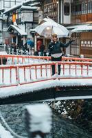 mulher turista visitando ginzan Onsen dentro Yamagata, feliz viajante passeios turísticos japonês Onsen Vila com neve dentro inverno temporada. ponto de referência e popular para atração dentro Japão. viagem e período de férias conceito foto