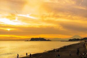 cenário kamakura Yuigahama de praia com kamakura cidade e Fujisan montanha. crepúsculo silhueta montar Fuji atrás enoshima ilha às Kamakura, Kanagawa, Japão. ponto de referência para turista atração perto Tóquio foto