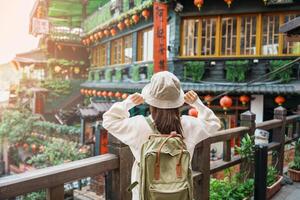 mulher viajante visitando dentro Taiwan, turista com chapéu e mochila passeios turísticos dentro Jiufen velho rua Vila com chá casa fundo. ponto de referência e popular atrações perto Taipei cidade. viagem conceito foto