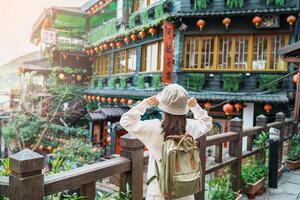 mulher viajante visitando dentro Taiwan, turista com chapéu e mochila passeios turísticos dentro Jiufen velho rua Vila com chá casa fundo. ponto de referência e popular atrações perto Taipei cidade. viagem conceito foto