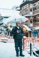 homem turista visitando ginzan Onsen dentro Yamagata, feliz viajante passeios turísticos japonês Onsen Vila com neve dentro inverno temporada. ponto de referência e popular para atração dentro Japão. viagem e período de férias conceito foto