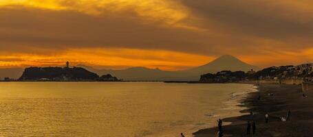 cenário kamakura Yuigahama de praia com kamakura cidade e Fujisan montanha. crepúsculo silhueta montar Fuji atrás enoshima ilha às Kamakura, Kanagawa, Japão. ponto de referência para turista atração perto Tóquio foto