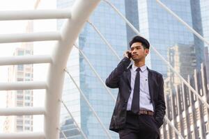 jovem o negócio homem usando Móvel Smartphone lado de fora escritório com embaçado cidade fundo foto
