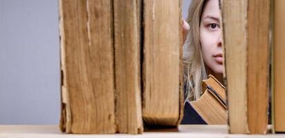 jovem mulher picaretas acima ou coloca a velho livro em a prateleira. biblioteca. seletivo foco. Alto qualidade foto