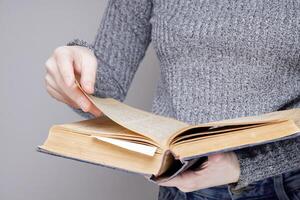 a mão do a invisível pessoa folhas através a Páginas do a velho e velho livro. dentro uma universidade ou escola biblioteca. Alto qualidade foto