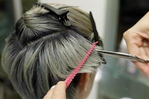 cabeleireiro mãos com pente e tesouras cortar a modelo cabelo. seletivo foco.alto qualidade foto