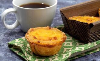 grande quantidade do sobremesas pastel de nata ou Português ovo azedo com uma branco copo do Preto café. pastel de belm é uma pequeno torta com uma crocantes sopro pastelaria crosta e uma creme creme enchimento. foto