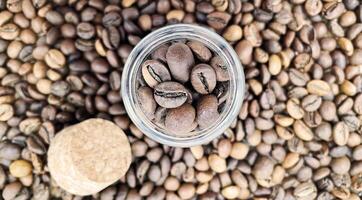 café feijões dentro uma pequeno vidro jarra com uma cortiça tampa em a mesa. café feijões embalado dentro uma transparente, hermético armazenamento recipiente. café sementes dentro uma vidro jar. plano layout. foto