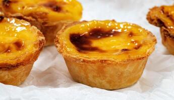 grande quantidade do recentemente cozido sobremesas pastel de nata ou Português ovo Tarte. pastel de belm é uma pequeno torta com uma crocantes sopro pastelaria crosta e uma creme creme enchimento. uma pequeno sobremesa, uma Bolinho. foto