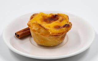 prato com 1 Português pastel de nata torta com creme e canela Gravetos. pastel de belém é a icônico em forma de xícara pastelaria com uma queimado topo e uma crocantes sopro pastelaria crosta. doce sobremesa. foto