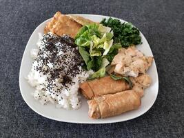 caseiro grelhado frango com grelhado abobrinha, verde salada, Primavera rolos, arroz Arroz a grega e salsinha. brócolis sementes em topo do a arroz Arroz a grega. foto