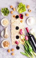 plano disposição do tradicional produtos para a judaico Páscoa feriado. vinho, matzoth pão, salsinha, alface, ovo, osso. topo vertical visualizar. foto