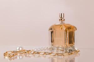a caro fragrância do mulheres ou masculino perfume dentro uma chique perfume garrafa em uma bege fundo com uma pérola colar. frente visualizar. uma cópia de espaço. foto