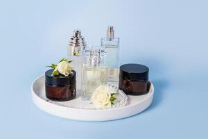 conjunto do natural orgânico facial pele Cuidado produtos dentro vários frascos e perfume em cerâmico branco bandeja e azul fundo. perfume e beleza conceito. foto
