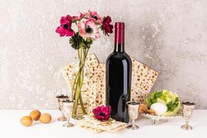 festivo ainda vida para a Primavera judaico feriado do páscoa. tradicional kosher comida, uma garrafa do vermelho vinho e prata tiro óculos com derramado vinho foto