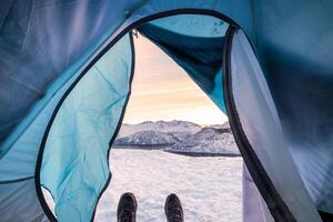 neve chuteiras relaxante dentro barraca acampamento Entrada com cenário neve cume às nascer do sol foto