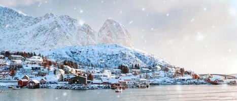 Visão do nórdico pescaria Vila em litoral com neve coberto montanha em inverno às reinar cidade, lofoten ilhas, Noruega foto