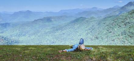 homem asiático viajar relaxar no feriado. durma relaxe no gramado da montanha. Na Tailândia foto