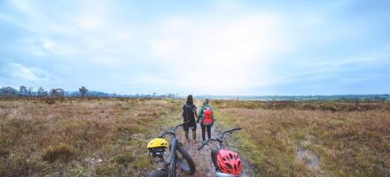 homens e mulheres asiáticas amantes viajam fotografia natureza. viaje relaxe ande em um deserto de bicicleta na selva.estar na linha. no prado na floresta. Tailândia foto