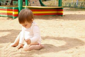 bebê jogando com areia em a Parque infantil foto