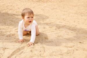 fofa pequeno bebê descalço em a areia com cópia de espaço foto