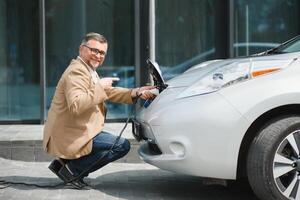 uma homem de negocios cobranças a elétrico carro foto