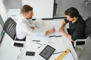 dois pessoas sentar dentro frente do construção plano e conversa sobre a arquitetura foto