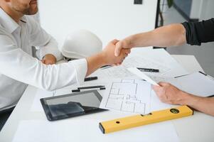 engenheiro ou arquiteto trabalho em equipe trabalhando em construção projeto com construção modelo e projeto dentro escritório. construção conceito. foto