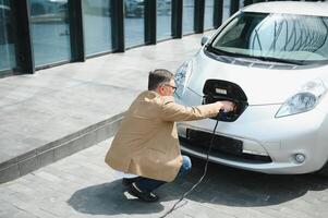 uma homem de negocios cobranças a elétrico carro foto